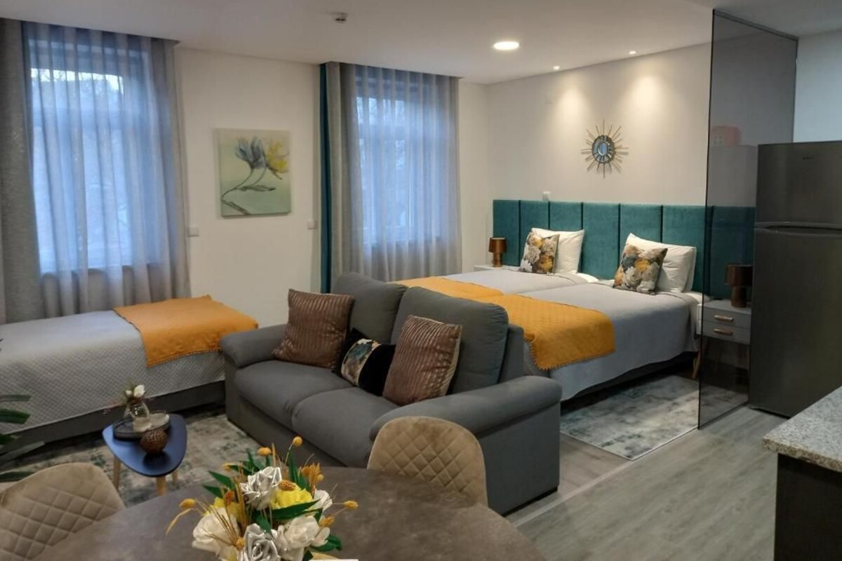 Una habitación de hotel con cama, sofá y una pequeña mesa de comedor.