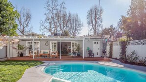A backyard with a swimming pool, a covered patio, and a lawn. - Adorable 3 bdr Home Universal Pool hot tub (Los Angeles)