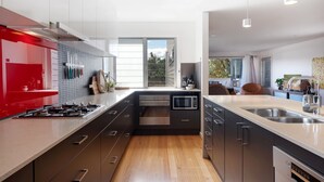 A modern kitchen with a central island, stainless steel appliances, and a red accent wall.
