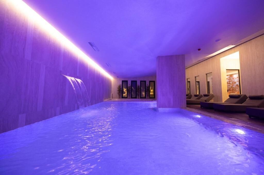 A spa area with a hot tub, seating, and a waterfall feature.