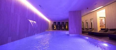 A spa area with a hot tub, seating, and a waterfall feature.