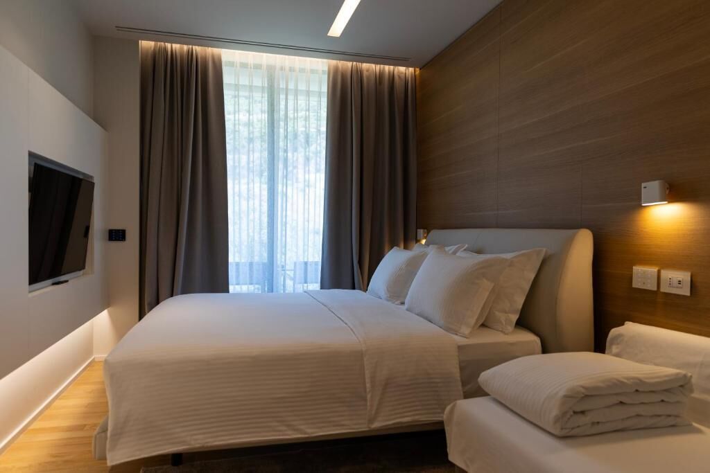 Una camera d'albergo con un letto grande, una TV fissata al muro e una testiera in legno.