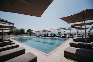 Una piscina al aire libre de temporada, sombrillas, tumbonas