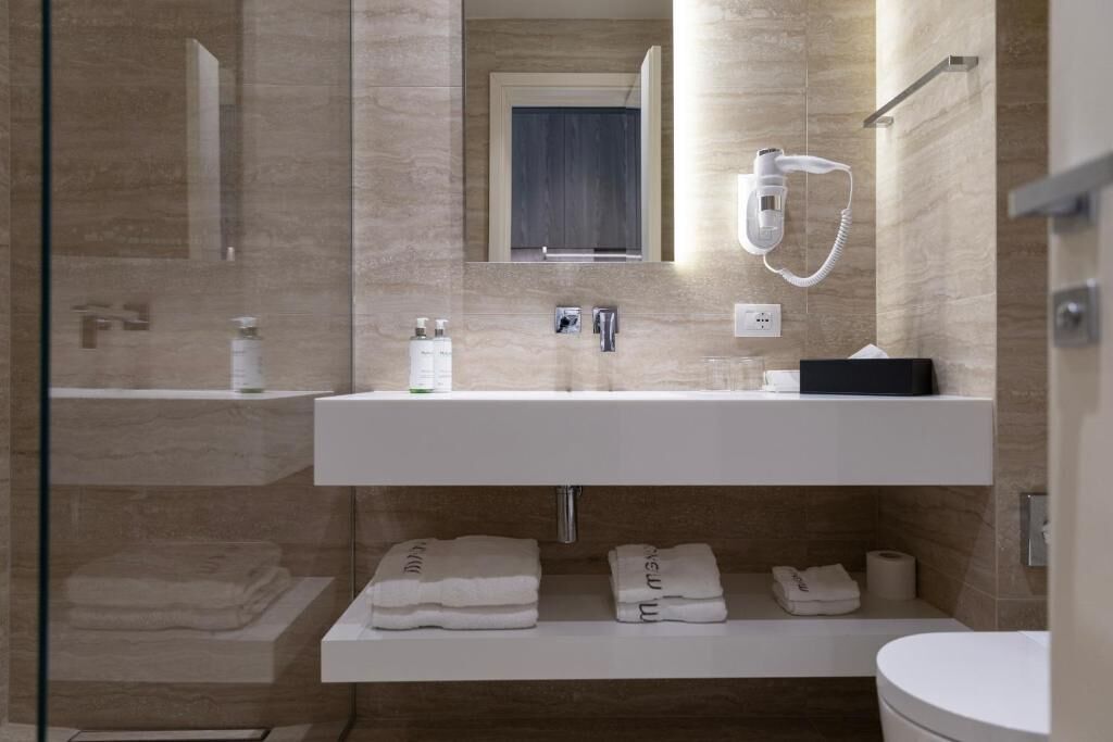 A modern bathroom with a glass shower enclosure, a white vanity with a mirror, and neatly folded towels.