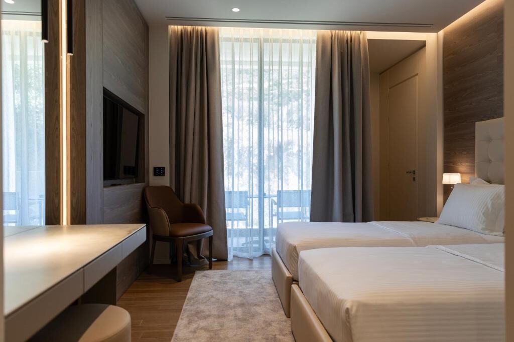 A hotel room with a bed, a desk, a chair, and a TV.