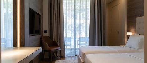 A hotel room with a bed, a desk, a chair, and a TV.