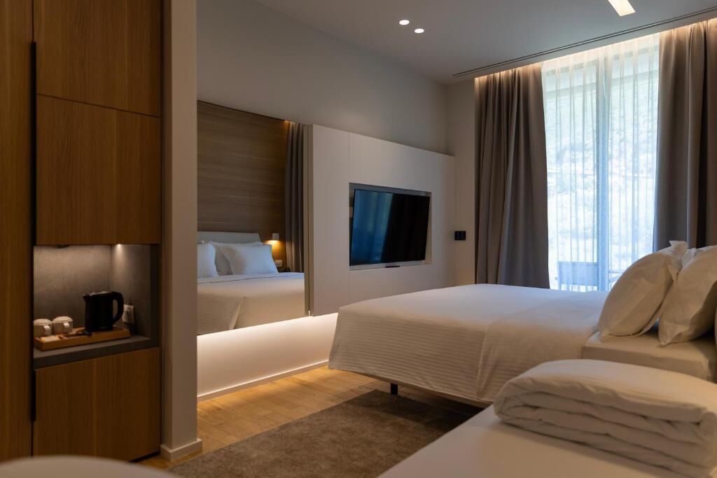 A hotel room with a bed, a TV, a wooden cabinet, and a window with curtains.