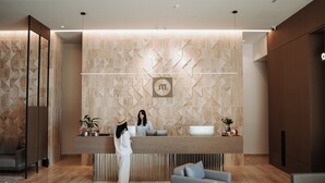 A modern reception area with a geometric patterned wall, a reception desk, and seating arrangements. - Magnus Hotel (Vlorë)