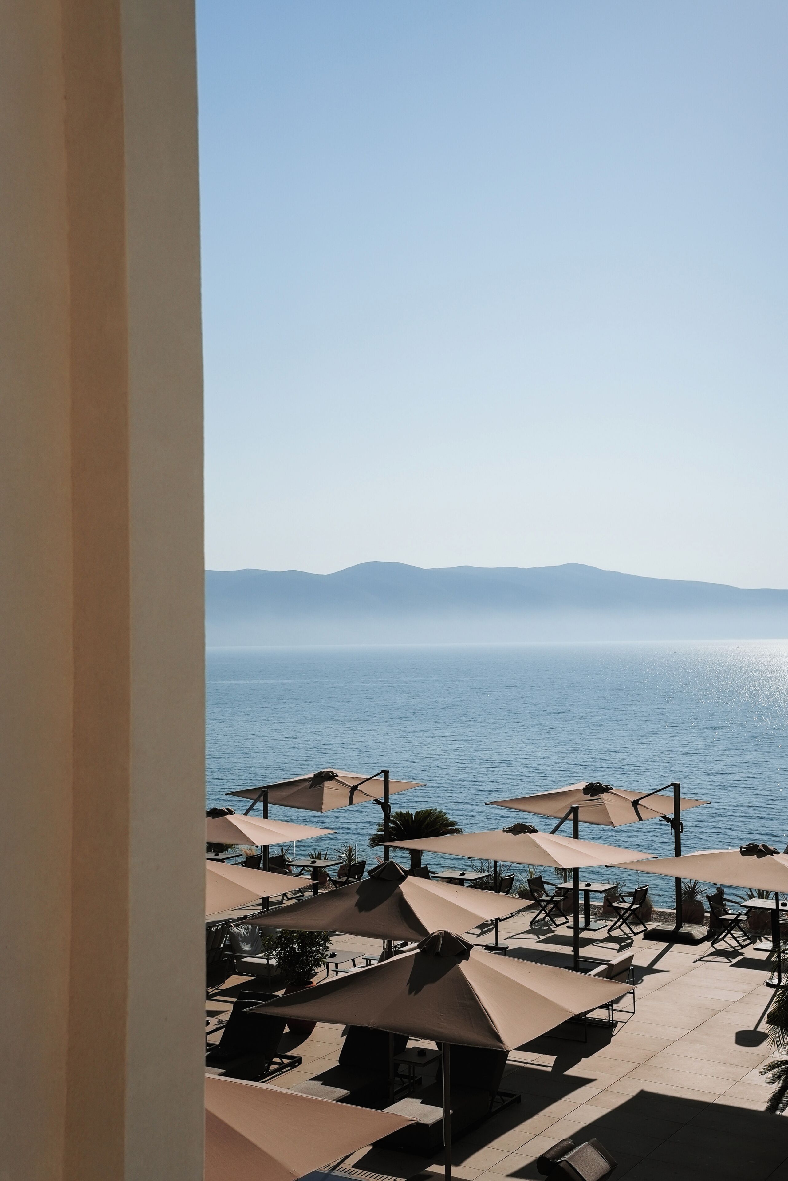 A seaside view with outdoor seating and umbrellas.