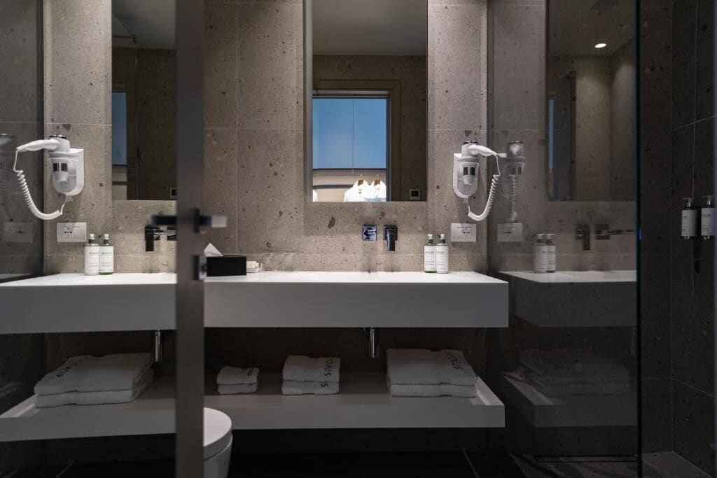 A modern bathroom with two sinks, a mirror, and a window.
