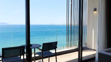Un balcon avec vue sur la mer, deux chaises et une table.