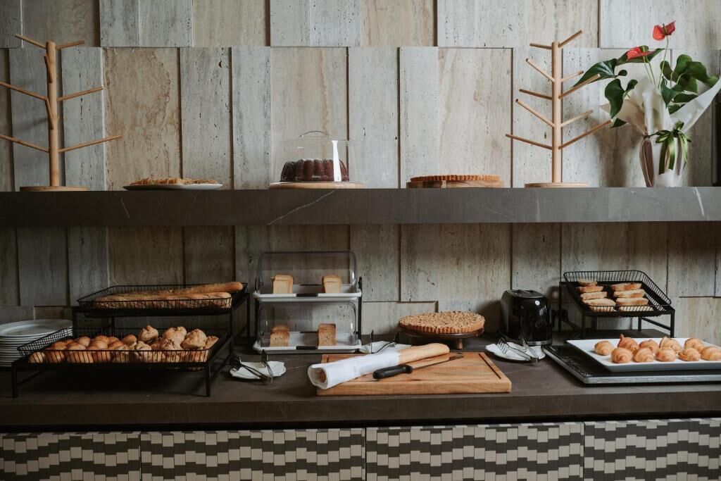 Montaje de bufé con diversos productos horneados, una máquina de café y una planta decorativa.