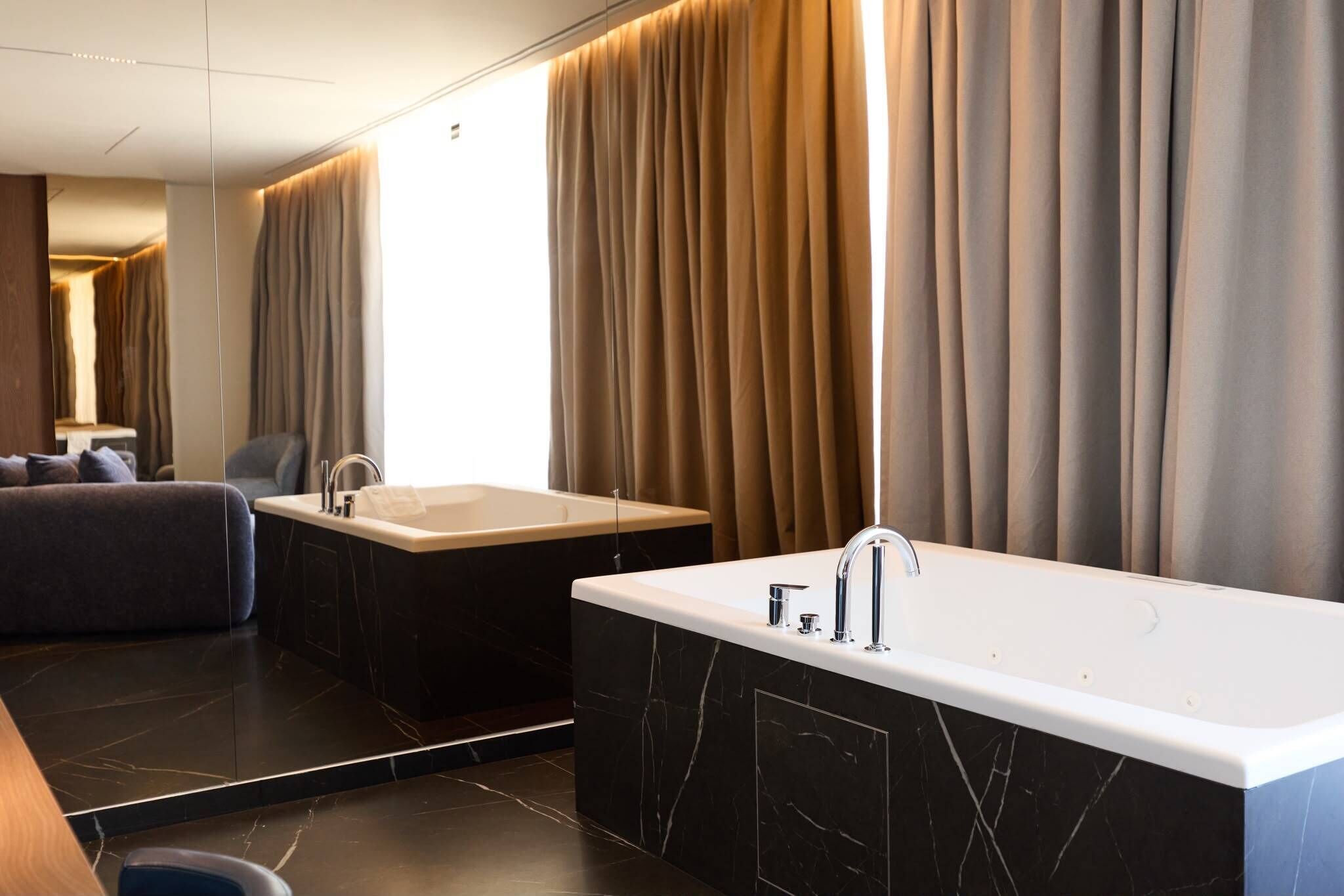 A modern bathroom with a large bathtub, a separate sink, and a mirror.