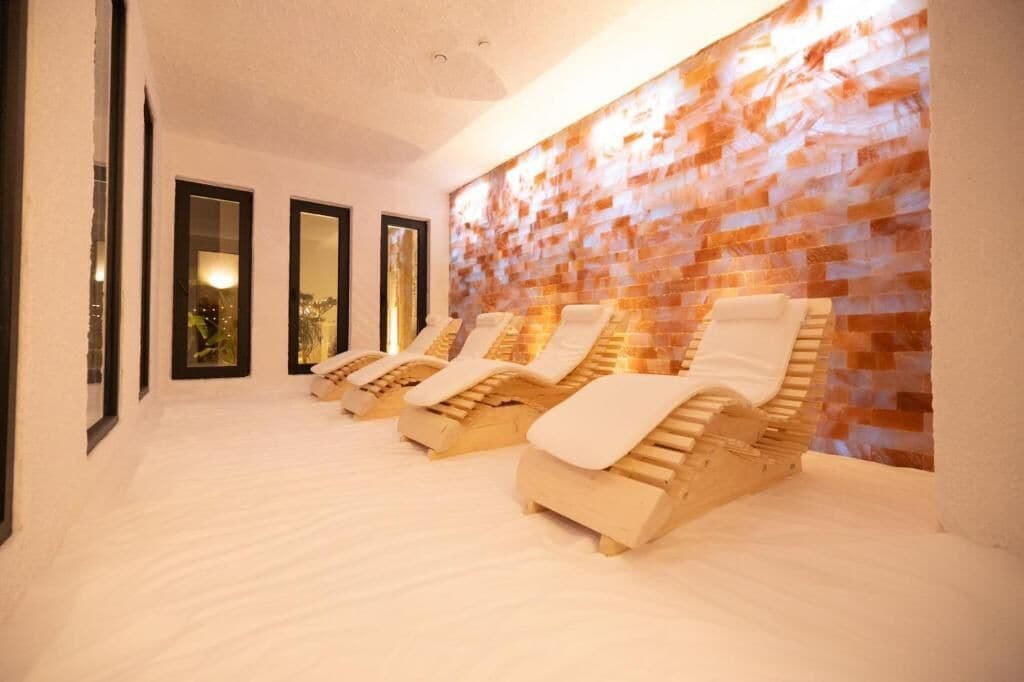 Uma área de spa com cadeiras reclináveis, parede texturizada e obras de arte emolduradas nas paredes.