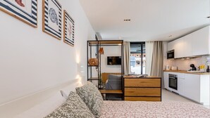 A compact living space with a bed, a sofa, a small dining area, and a kitchenette.