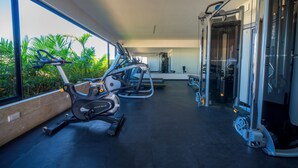 A gym with exercise equipment, large windows, and a view of greenery.