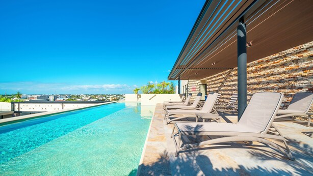 A poolside area with lounge chairs and a view of the ocean.