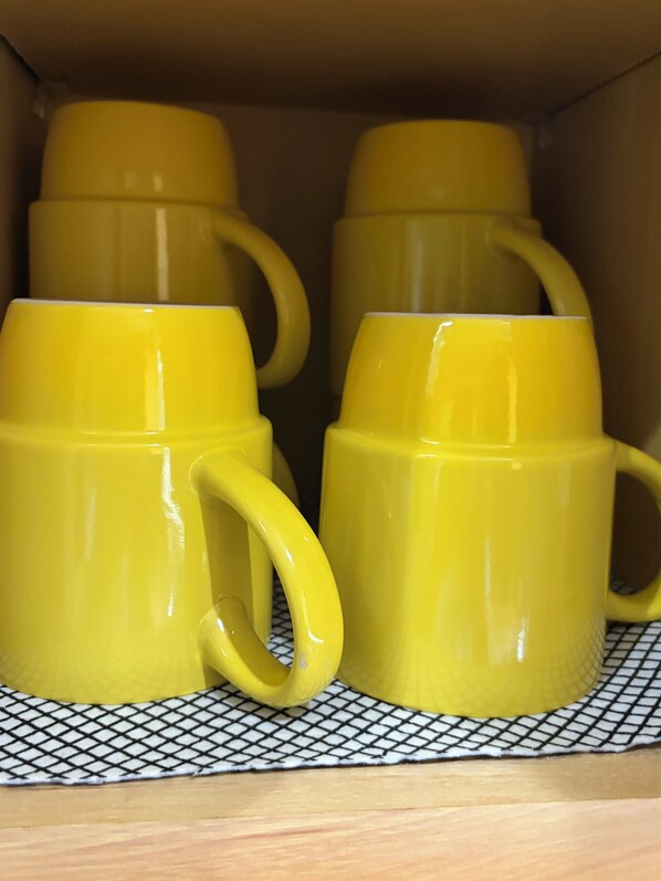 Une étagère avec quatre tasses jaunes.