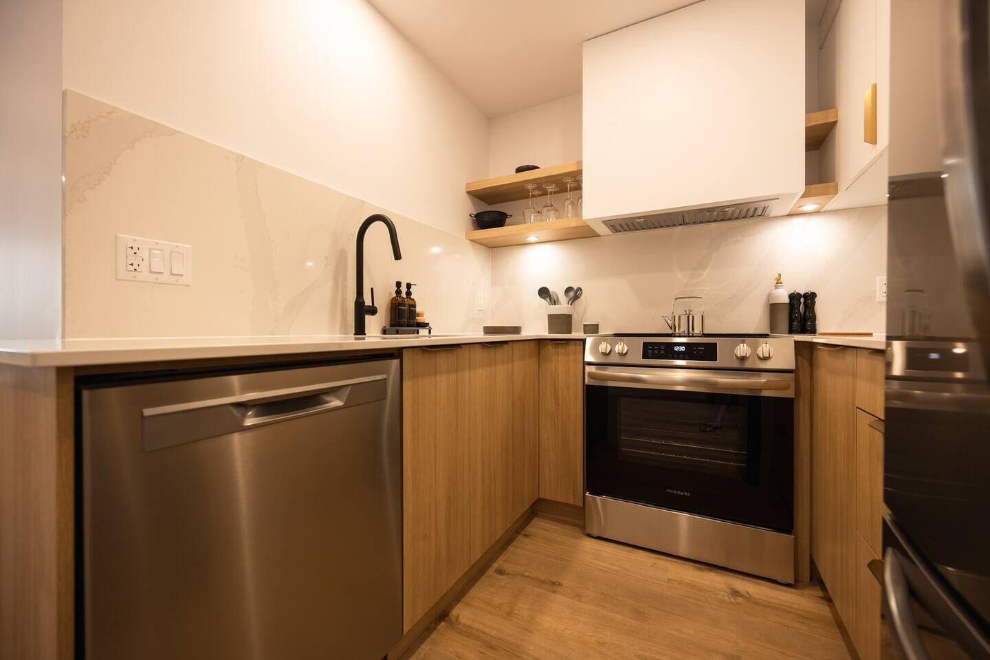 A modern kitchen with stainless steel appliances, wooden cabinets, and a built-in dishwasher.