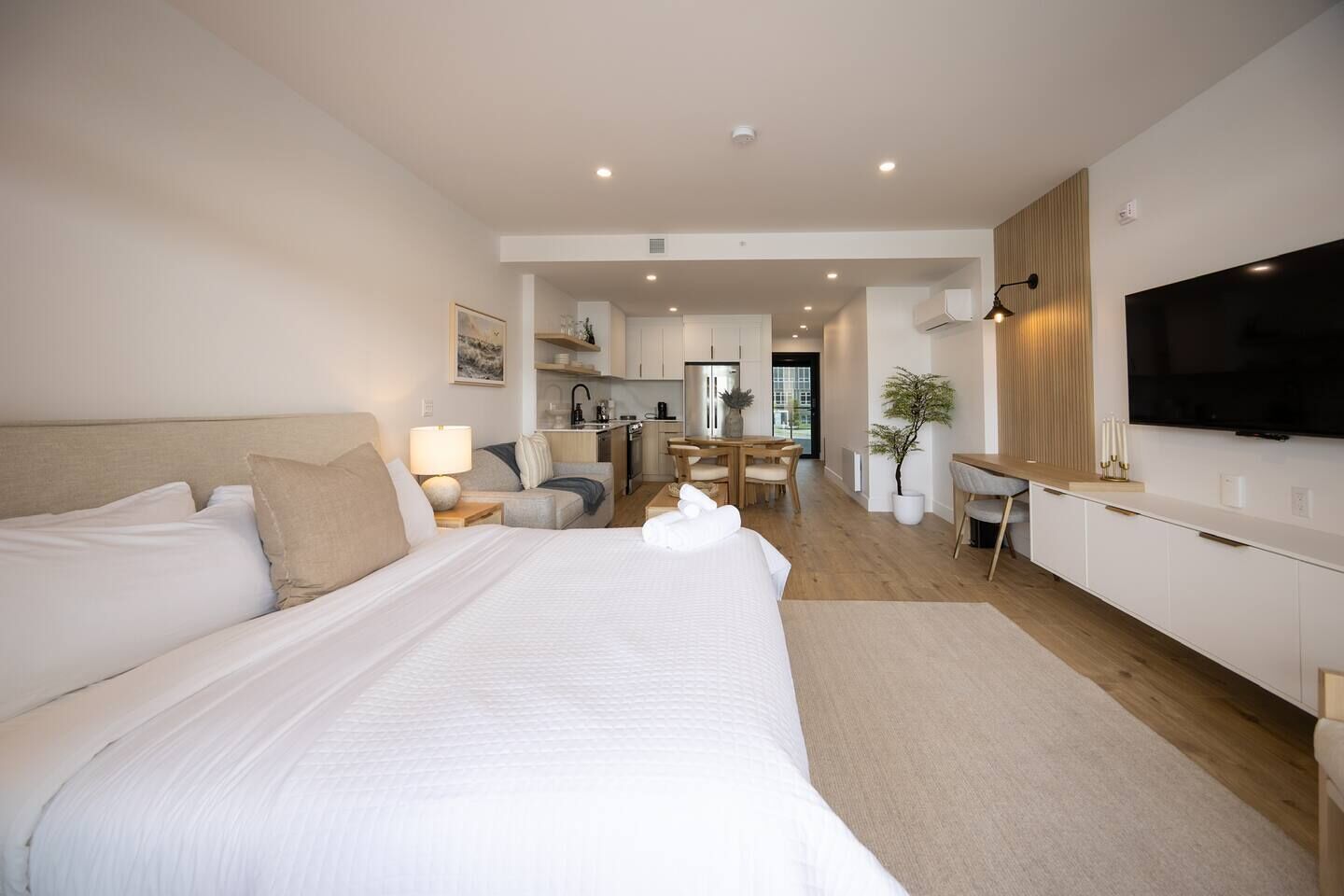 Une chambre d’hôtel avec un grand lit, un bureau, une télévision et une kitchenette.