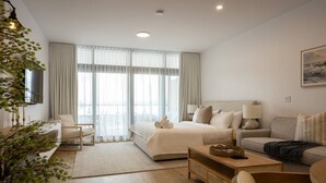 Una habitación de hotel moderna con una cama grande, un sofá, un escritorio y una mesa de comedor.