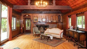 A wooden interior with a fireplace, a sofa, a chair, and a desk.