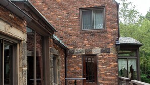 A brick building with large windows and a door, a small balcony, and a paved walkway.