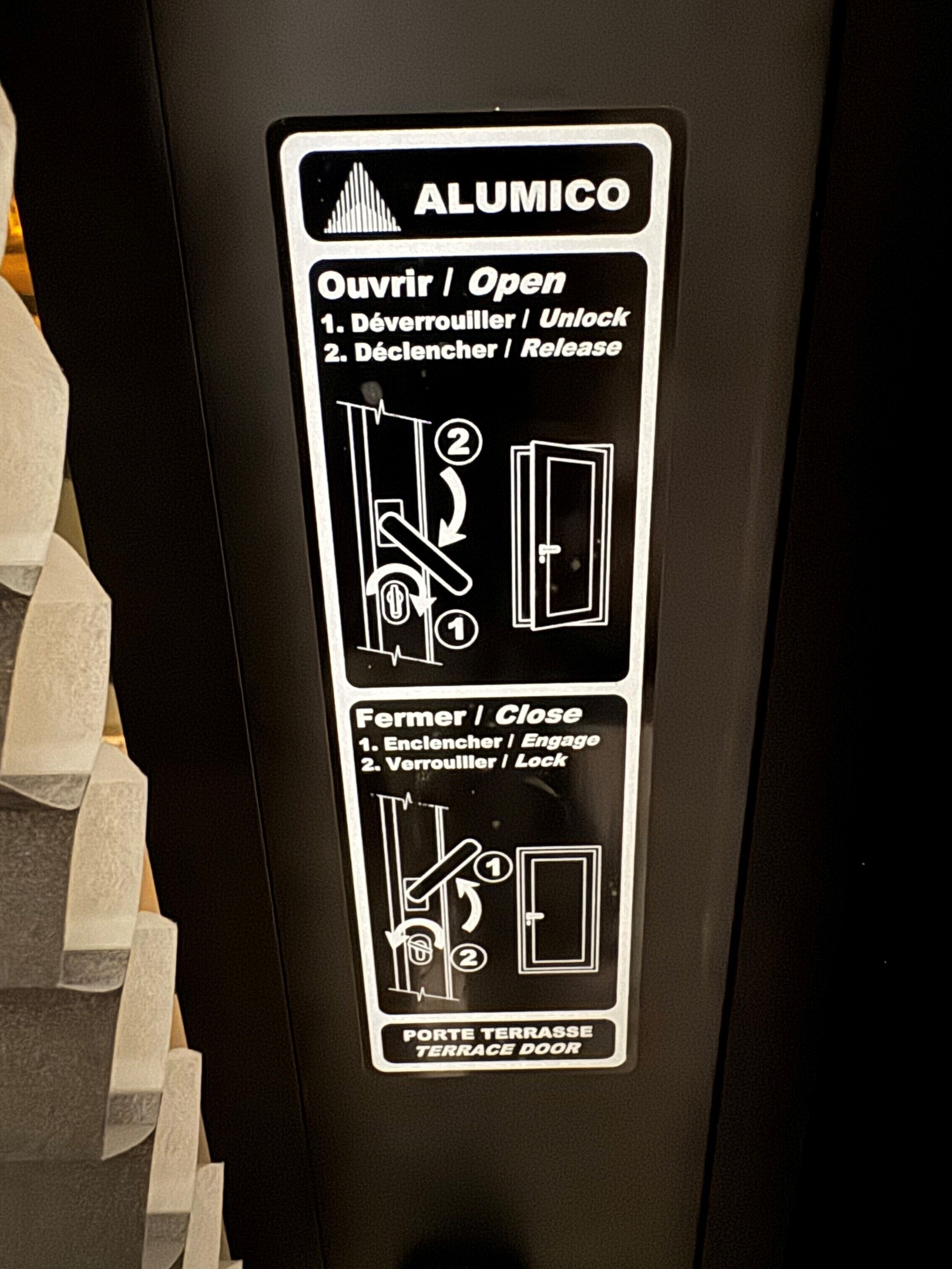 Une affiche indiquant les instructions pour l’utilisation d’une porte-fenêtre donnant sur une terrasse, y compris les étapes à suivre pour l’ouvrir et la fermer.