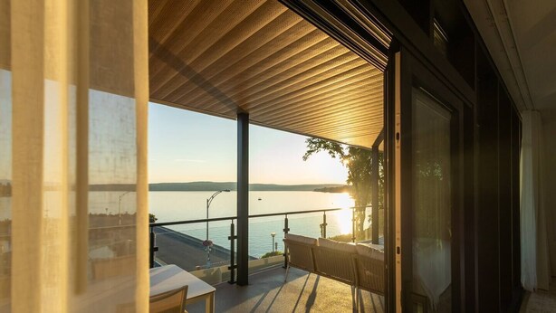Un balcon donnant sur une étendue d’eau et sur un coucher de soleil.
