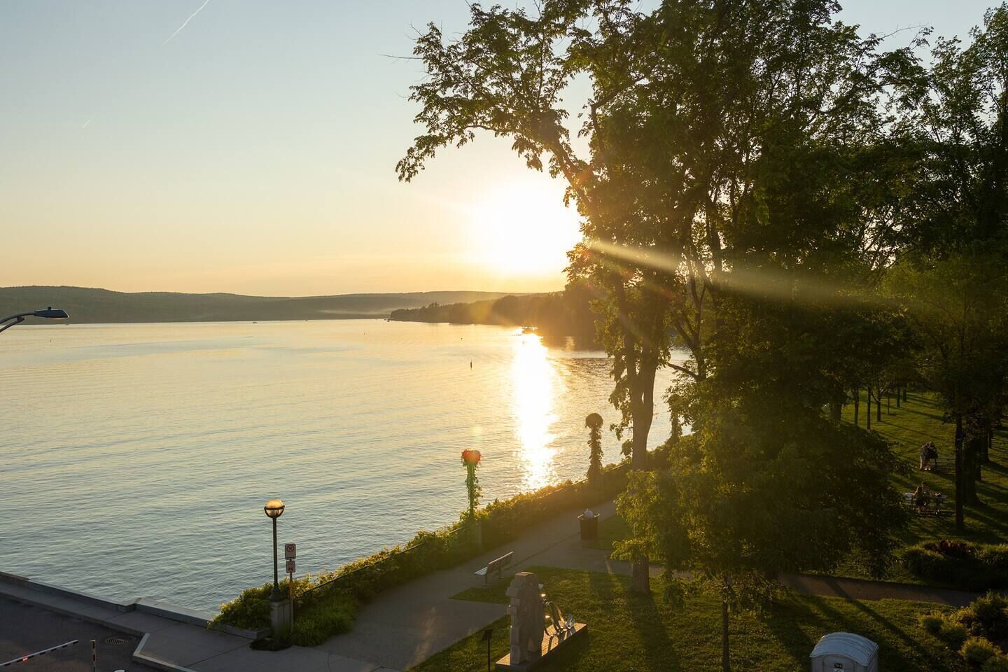 Une vue sur le fleuve, avec un coucher de soleil, un sentier pédestre et des arbres.