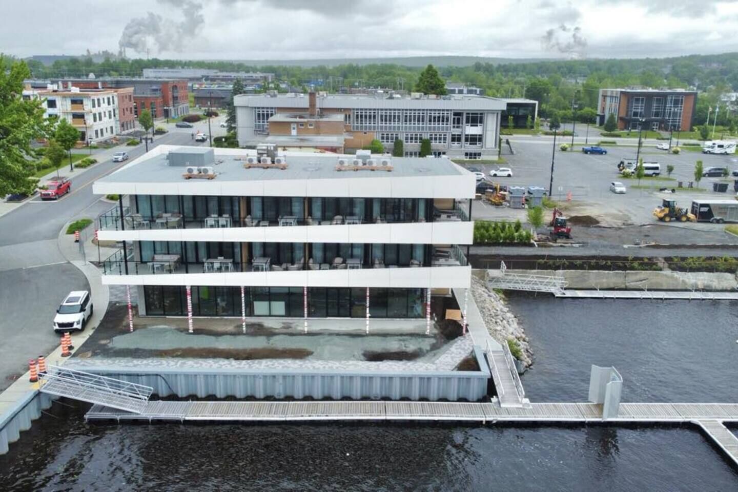 A modern building with a flat roof, large windows, and a dock extending into a body of water.