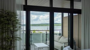 A hotel room with a balcony overlooking a lake, a sofa, and a small table. - La Capitainerie - Marina - 304 - Bord de l'eau (Lac-Mégantic)