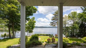 A covered outdoor area with a stone pathway leading to a grassy lawn and a view of a lake. - Aux mille et une étoiles (Piopolis)