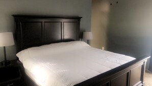 A bed with a dark headboard and white bedding, flanked by two bedside tables with lamps.
