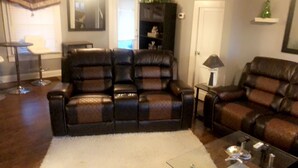 A living room with a dark brown leather sofa, a white rug, and a coffee table.
