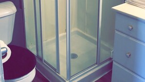 A bathroom with a glass-enclosed shower, a white toilet, and a white vanity with drawers.