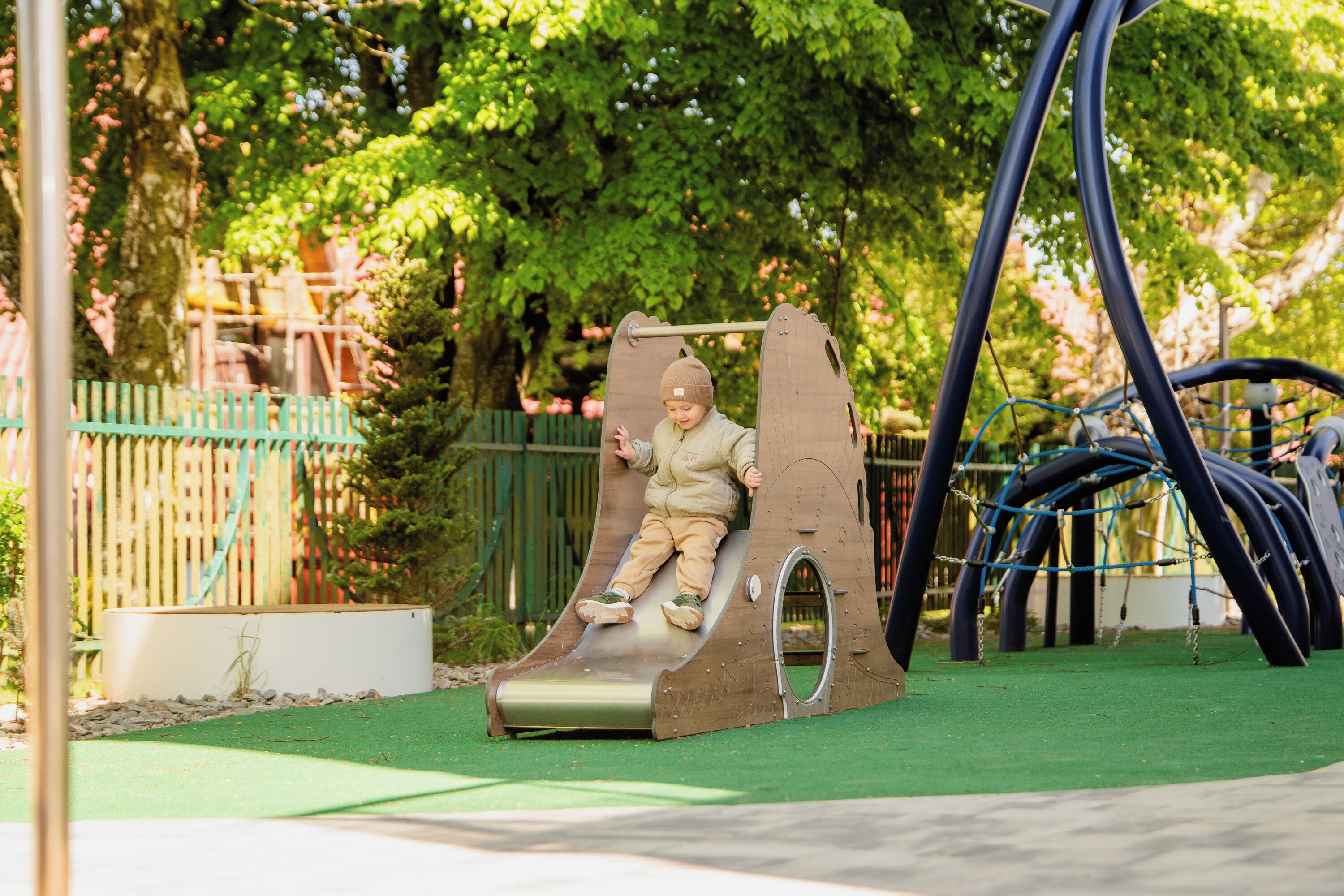 A playground with a slide, climbing structures, and a fenced area.