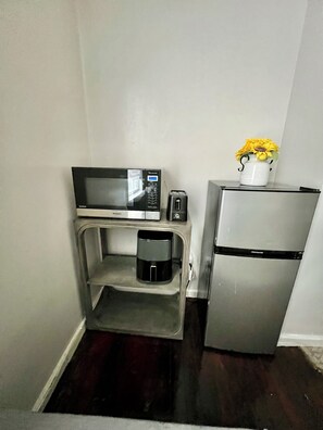 Une petite cuisine équipée d’un four à micro-ondes, d’un grille-pain, d’une machine à café et d’un réfrigérateur.