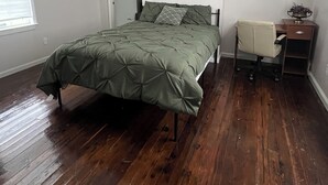 Un dormitorio con cama, escritorio, silla, ventilador de techo y radiador.