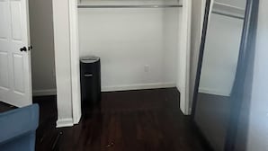 Una habitación con un armario blanco, una puerta y un cubo de basura.