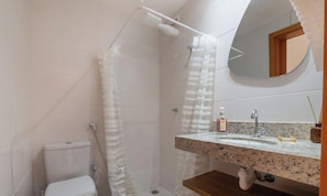 Une salle de bain avec douche, toilettes et lavabo.