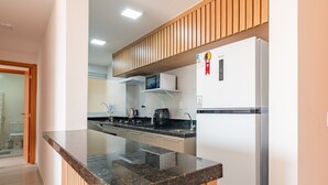 Een moderne keuken met een granieten aanrechtblad, witte kasten en een ingebouwde magnetron.