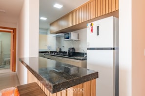 Una cocina moderna con encimera de granito, armarios blancos y un microondas integrado.