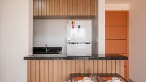 Una cucina compatta con mobili in legno, un frigorifero integrato e un piccolo angolo ristoro con tavolo e sedie.