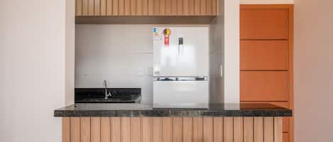 A compact kitchen with wooden cabinets, a built-in refrigerator, and a small dining area with a table and chairs.