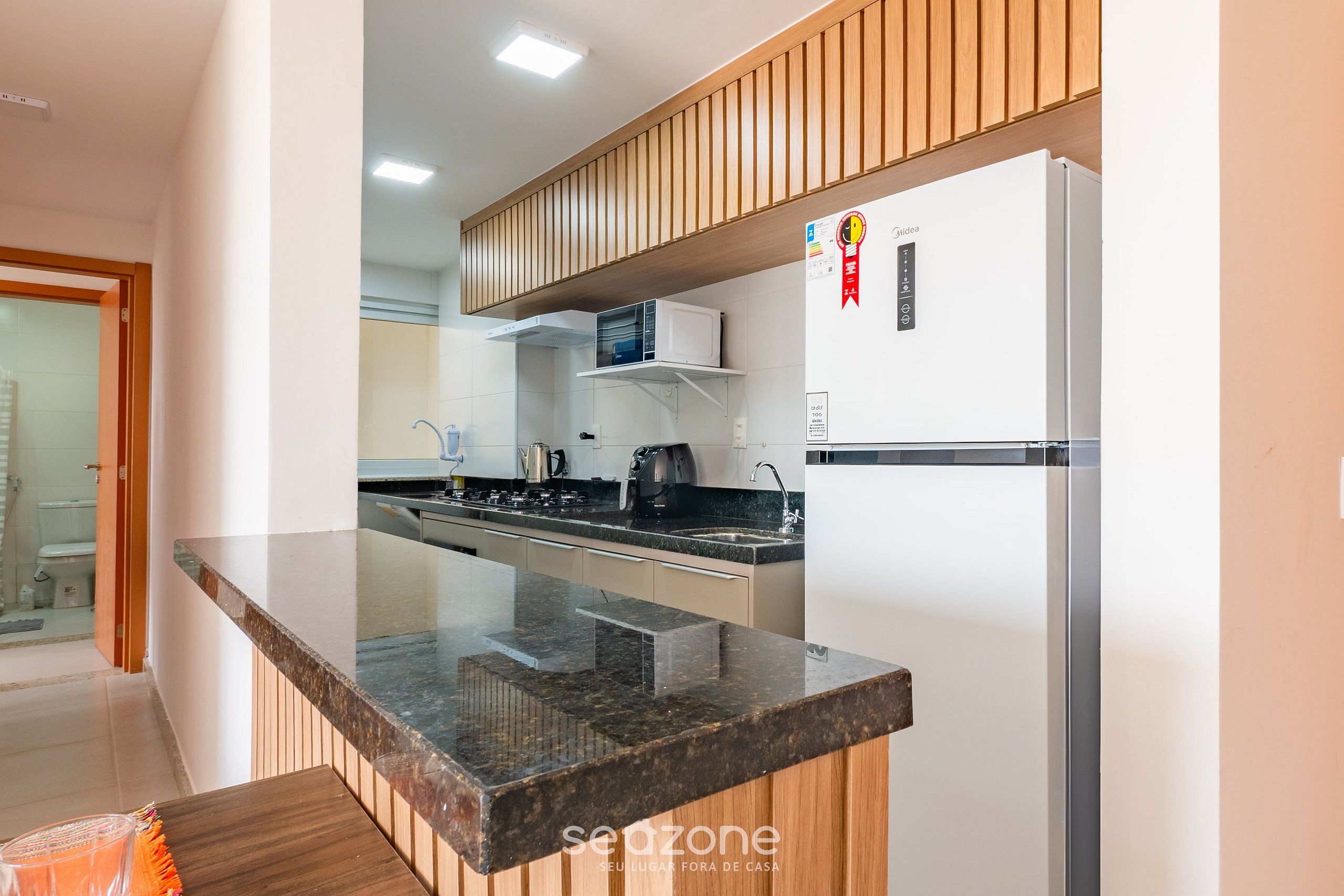 Cozinha moderna com bancada de granito, armários brancos e micro-ondas embutido.