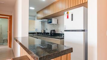 Cozinha moderna com bancada de granito, armários brancos e micro-ondas embutido.