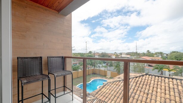 Un balcone con due sedie in vimini, una piscina e vista sul quartiere.