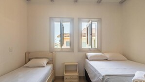A bedroom with two beds, a nightstand, and two windows. - Apt W/pool and Barbecue Near the Beach BA Art003 (Porto Seguro)