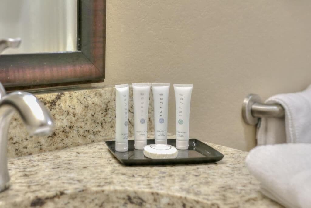 A bathroom sink with four toiletries on a tray.
